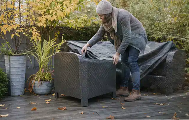 Person deckt Gartenmöbel vor der kalten Jahreszeit sorgfältig ab; Thema Poolchemie, Schwerpunkt Vergleich; Kontrolle.