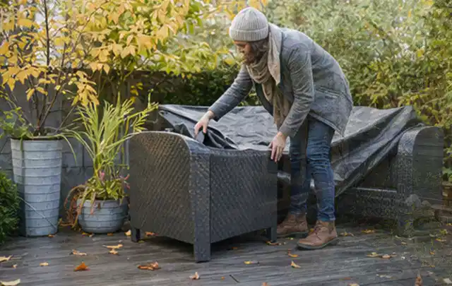 Person deckt Gartenmöbel vor der kalten Jahreszeit sorgfältig ab; Thema Poolfilter, Schwerpunkt Dimensionierung; Kontrolle.