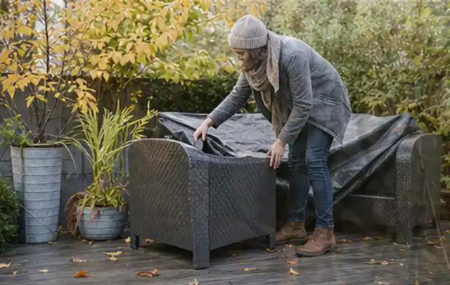Person deckt Gartenmöbel vor der kalten Jahreszeit sorgfältig ab; Thema Poolfilter, Schwerpunkt Kaufberatung; Umsetzung.