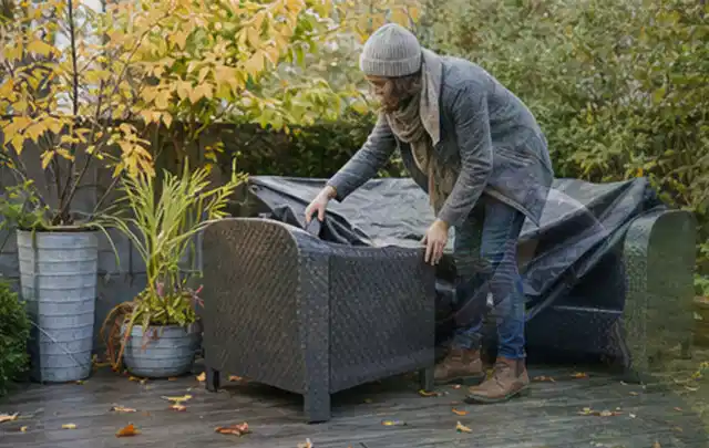 Person deckt Gartenmöbel vor der kalten Jahreszeit sorgfältig ab; Thema Poolfilter, Schwerpunkt Leistung; Ausgangslage.