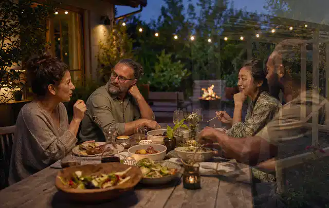 Menschen verbringen einen ruhigen Abend an einem Sitzplatz im Garten; Thema Poolheizungen, Schwerpunkt Ersatzteile; Ausgangslage.