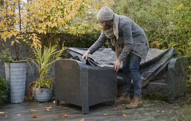 Person deckt Gartenmöbel vor der kalten Jahreszeit sorgfältig ab; Thema Poolheizungen, Schwerpunkt Kaufberatung; Ausgangslage.