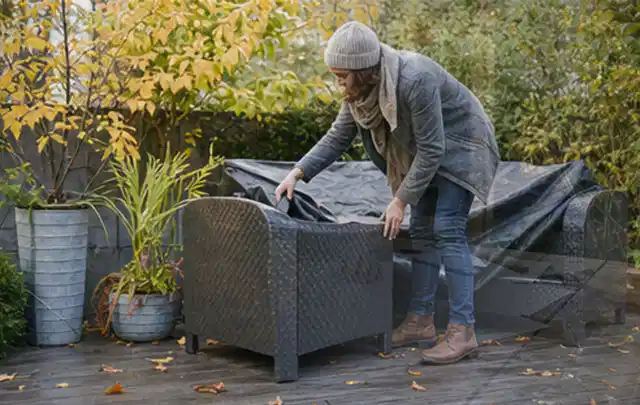 Person deckt Gartenmöbel vor der kalten Jahreszeit sorgfältig ab; Thema Poolheizungen, Schwerpunkt Leistung; Umsetzung.