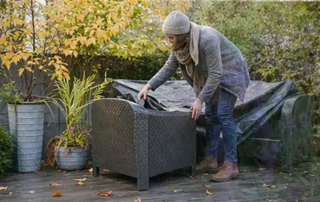 Person deckt Gartenmöbel vor der kalten Jahreszeit sorgfältig ab; Thema Poolheizungen, Schwerpunkt Sicherheit; Umsetzung.