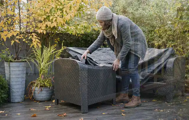 Person deckt Gartenmöbel vor der kalten Jahreszeit sorgfältig ab; Thema Poolheizungen, Schwerpunkt Systemvergleich; Umsetzung.