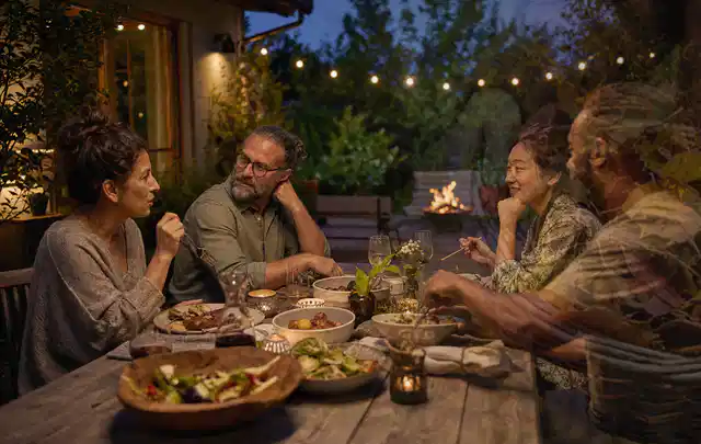Menschen verbringen einen ruhigen Abend an einem Sitzplatz im Garten; Thema Poolheizungen, Schwerpunkt Winterlager; Umsetzung.