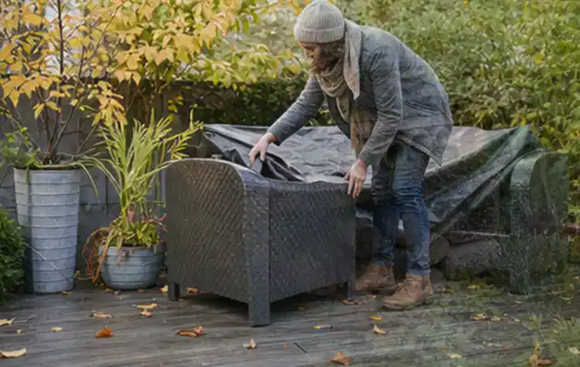 Person deckt Gartenmöbel vor der kalten Jahreszeit sorgfältig ab; Thema Poolpumpen, Schwerpunkt Reparatur; Ergebnis.