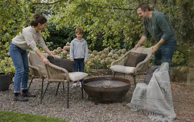 Familie stellt wetterfeste Sessel an einem geschützten Sitzplatz im Garten auf; Thema Poolpumpen, Schwerpunkt Sicherheit; Kontrolle.