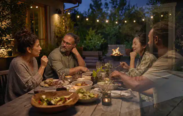 Menschen verbringen einen ruhigen Abend an einem Sitzplatz im Garten; Thema Poolpumpen, Schwerpunkt Systemvergleich; Ausgangslage.