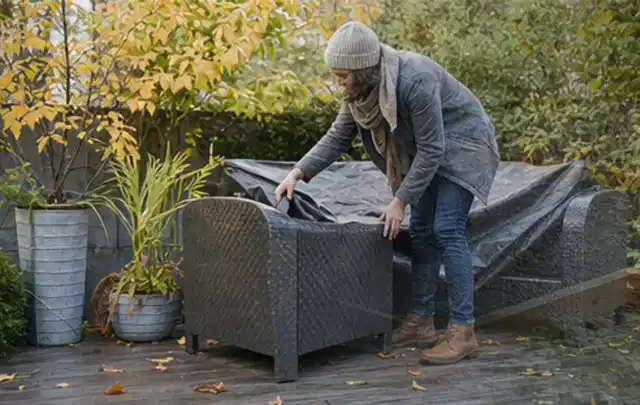Person deckt Gartenmöbel vor der kalten Jahreszeit sorgfältig ab; Thema Poolroboter, Schwerpunkt Checkliste; Umsetzung.