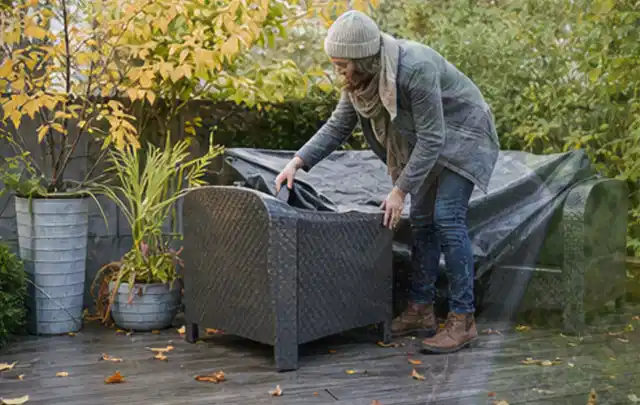 Person deckt Gartenmöbel vor der kalten Jahreszeit sorgfältig ab; Thema Poolroboter, Schwerpunkt Dimensionierung; Praxisalltag.