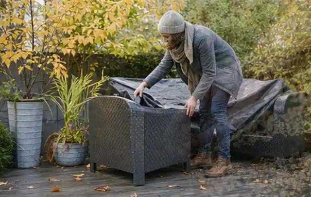 Person deckt Gartenmöbel vor der kalten Jahreszeit sorgfältig ab; Thema Poolroboter, Schwerpunkt Ersatzteile; Ausgangslage.