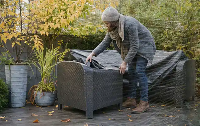 Person deckt Gartenmöbel vor der kalten Jahreszeit sorgfältig ab; Thema Poolroboter, Schwerpunkt Fehlerhilfe; Umsetzung.