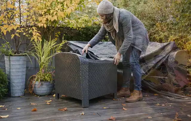 Person deckt Gartenmöbel vor der kalten Jahreszeit sorgfältig ab; Thema Poolroboter, Schwerpunkt Kaufberatung; Ausgangslage.