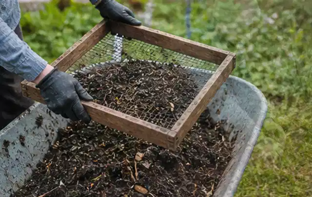 Behandschuhte Hände sieben reifen Kompost über einer Gartenschubkarre; Thema Radieschen, Schwerpunkt Saisonkalender; Ausgangslage.