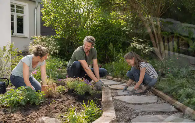 Familie geht auf einem Weg durch einen abwechslungsreich gestalteten Garten; Thema Rankpflanzen als Sichtschutz, Schwerpunkt Aufbau; Umsetzung.