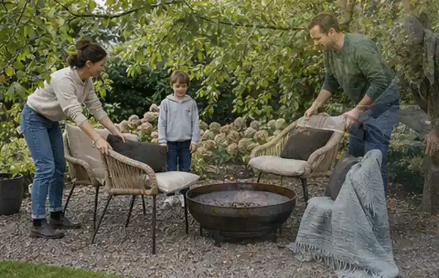 Familie stellt wetterfeste Sessel an einem geschützten Sitzplatz im Garten auf; Thema Rankpflanzen als Sichtschutz, Schwerpunkt Nachhaltigkeit;…