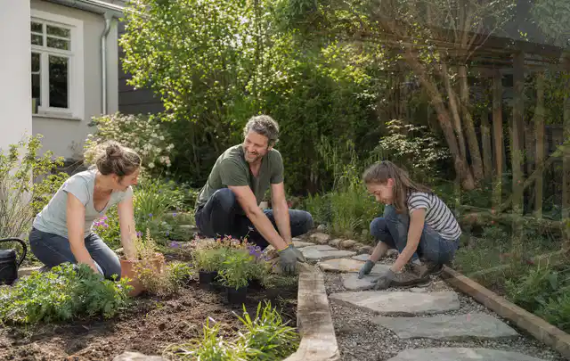 Familie geht auf einem Weg durch einen abwechslungsreich gestalteten Garten; Thema Rankpflanzen als Sichtschutz, Schwerpunkt Standort; Kontrolle.