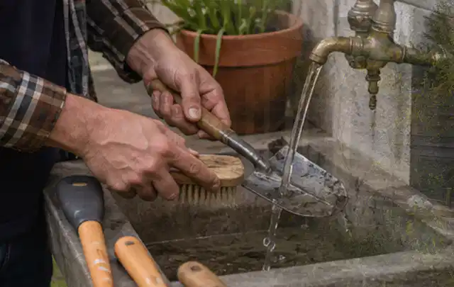 Hände reinigen gebrauchte Gartengeräte mit Bürste und Wasser am Außenbecken; Thema Rasenmäher, Schwerpunkt Testkriterien; Ergebnis.