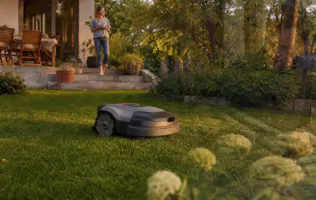 Mähroboter fährt am Abend über einen Rasen im Familiengarten; Thema RTK Mähroboter, Schwerpunkt Dimensionierung; Umsetzung.