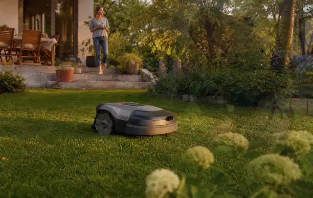 Mähroboter fährt am Abend über einen Rasen im Familiengarten; Thema RTK Mähroboter, Schwerpunkt Ersatzteile; Ergebnis.