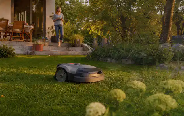 Mähroboter fährt am Abend über einen Rasen im Familiengarten; Thema RTK Mähroboter, Schwerpunkt Reparatur; Ausgangslage.