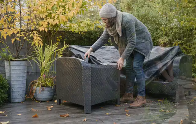 Person deckt Gartenmöbel vor der kalten Jahreszeit sorgfältig ab; Thema Salzwasserpools, Schwerpunkt Winterlager; Ergebnis.