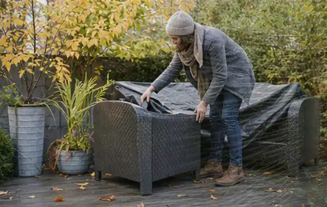 Person deckt Gartenmöbel vor der kalten Jahreszeit sorgfältig ab; Thema Sandfilteranlagen, Schwerpunkt Gärten mit kleiner Fläche; Ausgangslage.