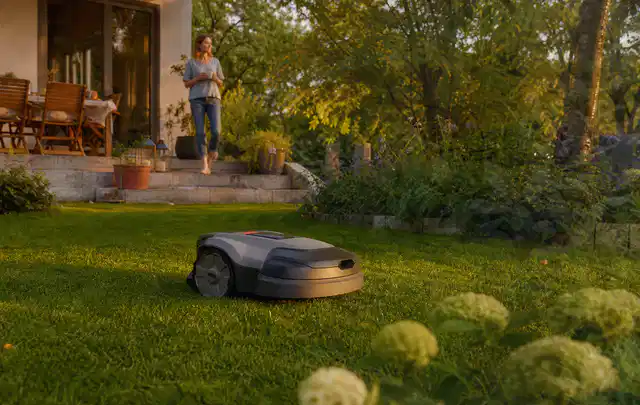 Mähroboter fährt am Abend über einen Rasen im Familiengarten; Thema Segway Navimow, Schwerpunkt Checkliste; Kontrolle.