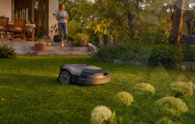 Mähroboter fährt am Abend über einen Rasen im Familiengarten; Thema Segway Navimow, Schwerpunkt Dimensionierung; Praxisalltag.