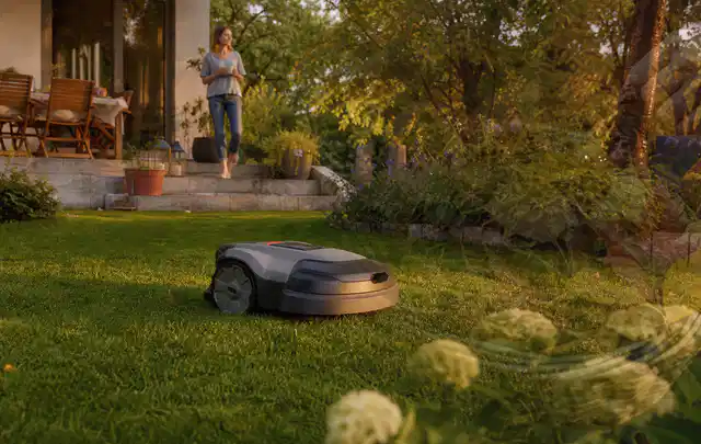 Mähroboter fährt am Abend über einen Rasen im Familiengarten; Thema Segway Navimow, Schwerpunkt Leistung; Umsetzung.