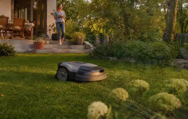 Mähroboter fährt am Abend über einen Rasen im Familiengarten; Thema Segway Navimow, Schwerpunkt Systemvergleich; Kontrolle.