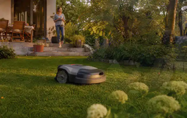 Mähroboter fährt am Abend über einen Rasen im Familiengarten; Thema Segway Navimow, Schwerpunkt Wartung; Ergebnis.