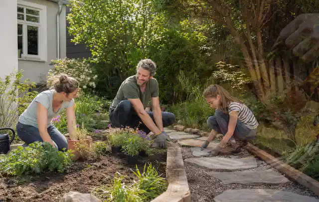 Familie geht auf einem Weg durch einen abwechslungsreich gestalteten Garten; Thema Sichtschutz aus Holz, Schwerpunkt DIY; Ausgangslage.