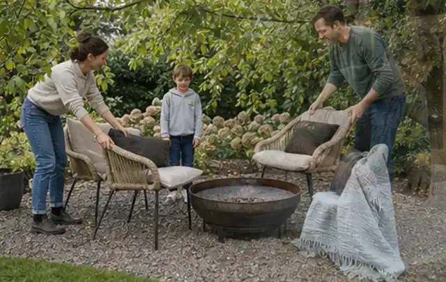 Familie stellt wetterfeste Sessel an einem geschützten Sitzplatz im Garten auf; Thema Sichtschutz aus Holz, Schwerpunkt Gestaltung; Umsetzung.