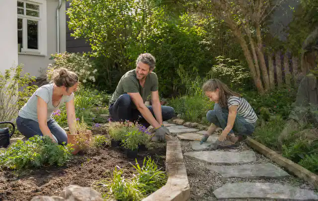 Familie geht auf einem Weg durch einen abwechslungsreich gestalteten Garten; Thema Sichtschutz aus Holz, Schwerpunkt Materialwahl; Ergebnis.
