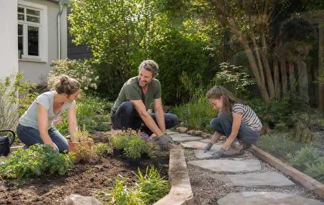 Familie geht auf einem Weg durch einen abwechslungsreich gestalteten Garten; Thema Sichtschutzhecken, Schwerpunkt DIY; Kontrolle.