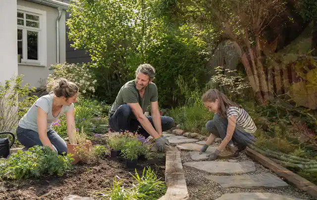 Familie geht auf einem Weg durch einen abwechslungsreich gestalteten Garten; Thema Sichtschutzmatten, Schwerpunkt Aufbau; Umsetzung.