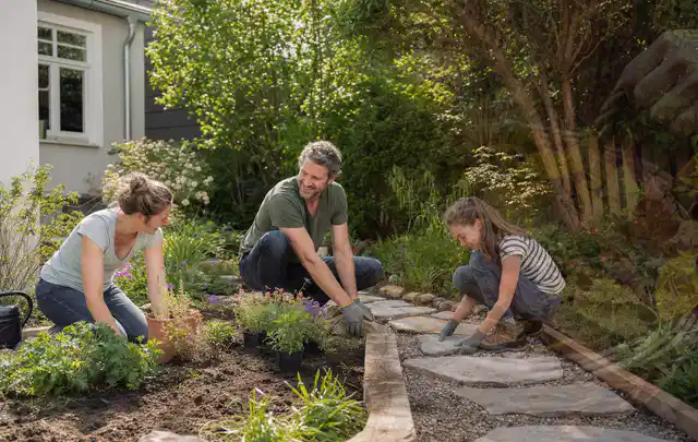 Familie geht auf einem Weg durch einen abwechslungsreich gestalteten Garten; Thema Sichtschutzmatten, Schwerpunkt Baurecht; Umsetzung.