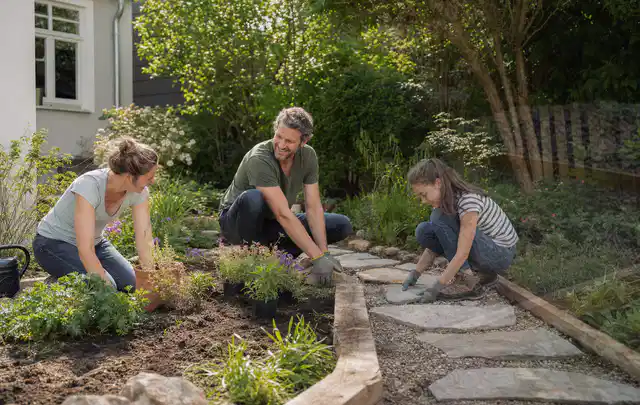 Familie geht auf einem Weg durch einen abwechslungsreich gestalteten Garten; Thema Sichtschutzmatten, Schwerpunkt Dimensionierung; Ergebnis.