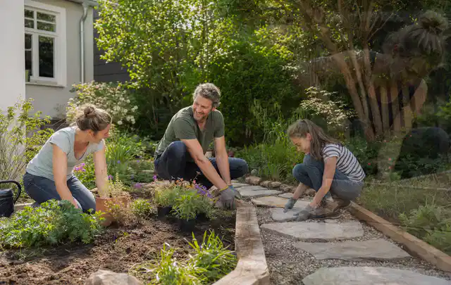 Familie geht auf einem Weg durch einen abwechslungsreich gestalteten Garten; Thema Sichtschutzmatten, Schwerpunkt Kosten; Praxisalltag.