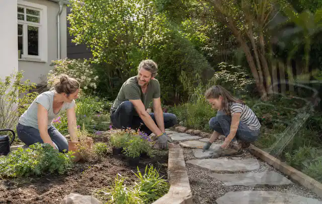 Familie geht auf einem Weg durch einen abwechslungsreich gestalteten Garten; Thema Sichtschutzmatten, Schwerpunkt Pflege; Ergebnis.