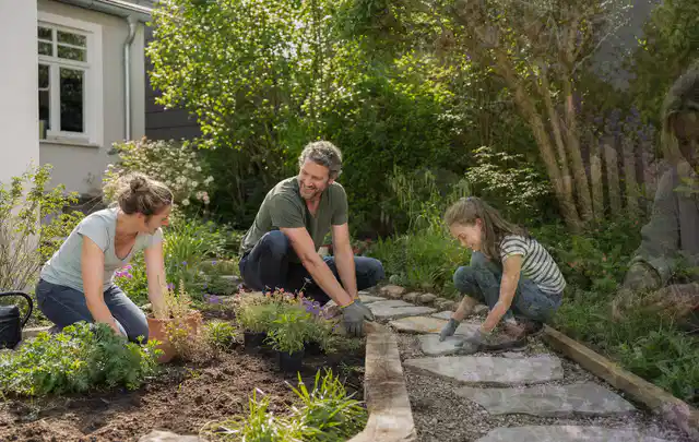 Familie geht auf einem Weg durch einen abwechslungsreich gestalteten Garten; Thema Sichtschutzmatten, Schwerpunkt Standort; Kontrolle.