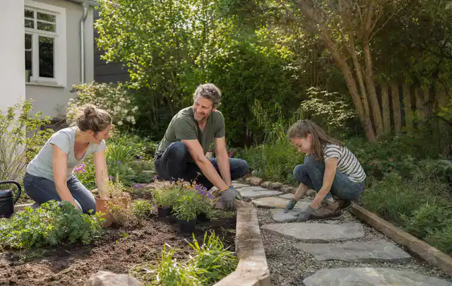 Familie geht auf einem Weg durch einen abwechslungsreich gestalteten Garten; Thema Sichtschutzmatten, Schwerpunkt Winterschutz; Kontrolle.