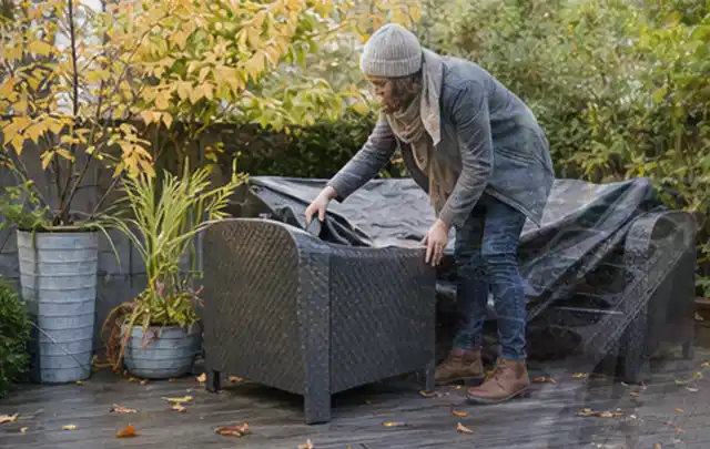 Person deckt Gartenmöbel vor der kalten Jahreszeit sorgfältig ab; Thema Smoker, Schwerpunkt Anwendung; Ergebnis.