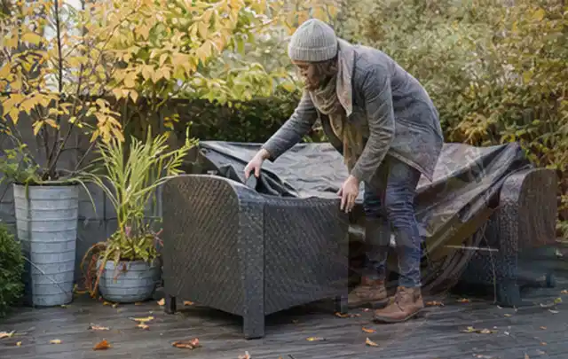 Person deckt Gartenmöbel vor der kalten Jahreszeit sorgfältig ab; Thema Smoker, Schwerpunkt Dimensionierung; Umsetzung.
