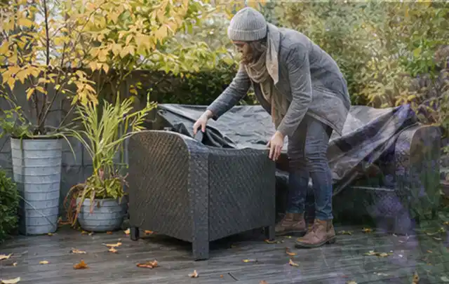 Person deckt Gartenmöbel vor der kalten Jahreszeit sorgfältig ab; Thema Smoker, Schwerpunkt Leistung; Ausgangslage.
