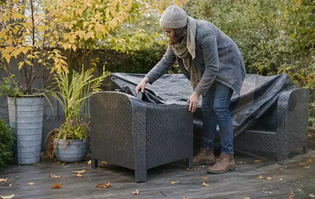 Person deckt Gartenmöbel vor der kalten Jahreszeit sorgfältig ab; Thema Smoker, Schwerpunkt Systemvergleich; Umsetzung.