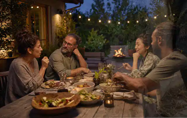 Menschen verbringen einen ruhigen Abend an einem Sitzplatz im Garten; Thema Smoker, Schwerpunkt Wartung; Praxisalltag.