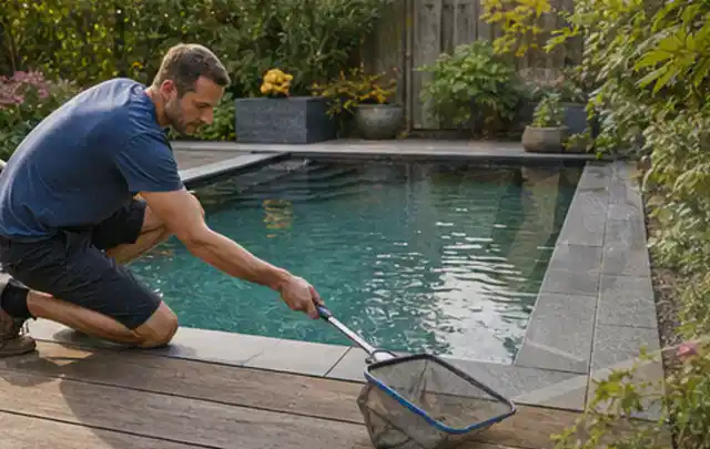 Person entfernt Blätter mit einem Kescher aus einem kleinen Gartenpool; Thema Sonnenschirme, Schwerpunkt Nachhaltigkeit; Praxisalltag.